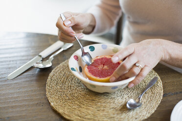 Frau isst Grapefruit mit Löffel - HOXF03572
