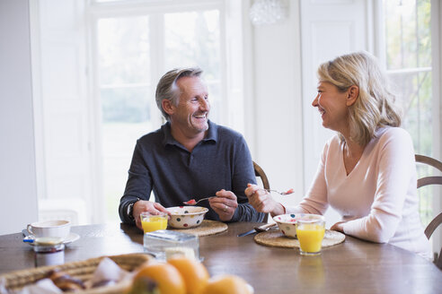 Lächelndes reifes Paar beim Frühstück und Gespräch am Esstisch - HOXF03577