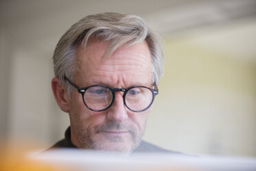 Fokussierter reifer Mann mit Brille arbeitet am Laptop - HOXF03578