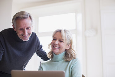 Smiling mature couple using laptop - HOXF03602