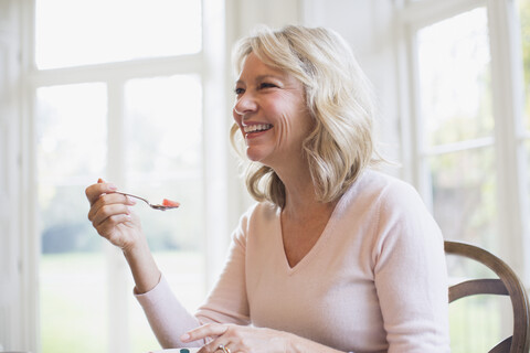 Glückliche reife Frau isst Obst, lizenzfreies Stockfoto