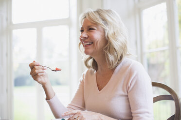 Happy mature woman eating fruit - HOXF03605