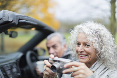Lächelndes Seniorenpaar mit Digitalkamera im Cabrio - CAIF20526