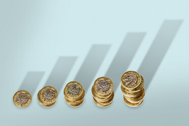 Ascending stacks of pound coins with bar graph growth shadow - CAIF20538