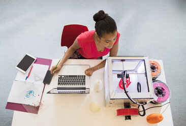 Female designer at laptop watching 3D printer - CAIF20594