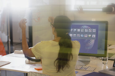 Weibliche Designerin betrachtet Transparenzdiagramm am Computer im Büro - CAIF20604