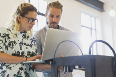 Designers with laptop at 3D printer in office - CAIF20614