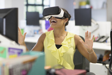 Enthusiastic businesswoman using virtual reality simulator glasses in office - CAIF20626