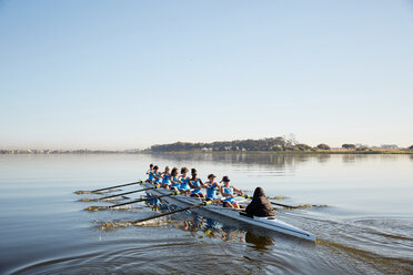 Female rowing team rowing scull on tranquil lake - CAIF20639