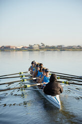 Female rowers rowing scull on sunny lake - CAIF20666