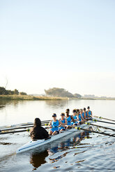 Female rowers rowing scull on sunny lake - CAIF20676