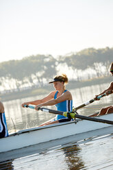 Determined female rower rowing scull on lake - CAIF20677