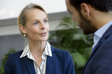 Businesswoman and man meeting in office atrium - CUF09866