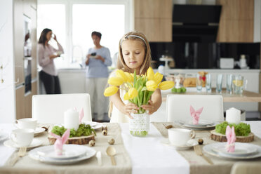 Mädchen arrangiert gelbe Tulpen am Esstisch zu Ostern - CUF09976