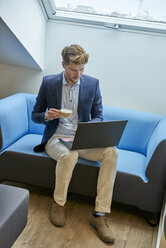 Geschäftsmann sitzt mit einer Tasse Kaffee auf der Couch und schaut auf seinen Laptop - BEF00070