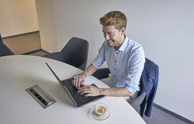 Lächelnder Geschäftsmann, der im Sitzungssaal am Laptop arbeitet - BEF00074