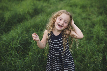 Girl looking up at camera on green grassy field - CUF09990