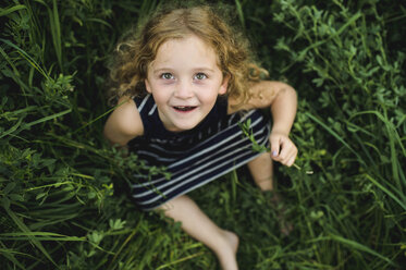 Girl looking up at camera on green grassy field - CUF09991