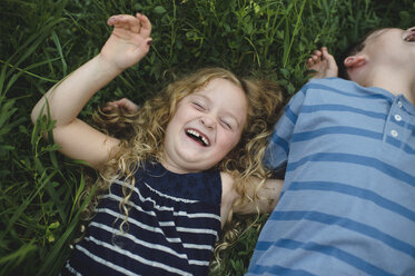 Brother and sister enjoying outdoors on green grassy field - CUF09993