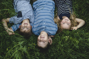Brothers and sister enjoying outdoors on green grassy field - CUF09994