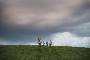 Family of five enjoying outdoors on green grassy field - CUF09997