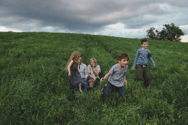 Family of five enjoying outdoors on green grassy field - CUF09999