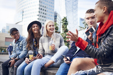 Five young adult friends sitting on wall chatting in city - CUF10021