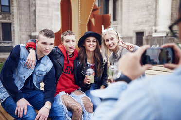 Over shoulder view of young man photographing young adult friends in city - CUF10024