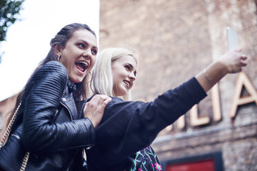 Two young women taking smartphone selfie on city street - CUF10031