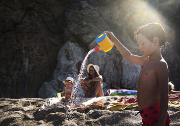 Junge am Strand, der eine Spielzeuggießkanne besprüht, Begur, Katalonien, Spanien - CUF10036