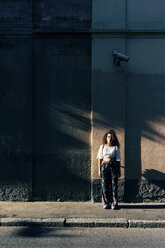 Frau steht im Schatten eines Gebäudes, Mailand, Italien - CUF10042