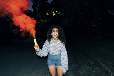 Woman holding flare in park at night - CUF10059