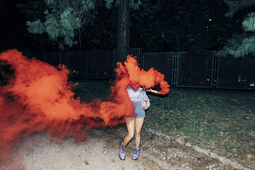 Woman holding flare in park at night - CUF10061