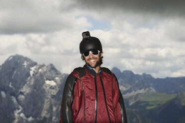 Portrait of base jumper wearing wingsuit with action camera on helmet, Dolomite mountains, Canazei, Trentino Alto Adige, Italy, Europe - CUF10065