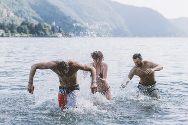 Three young adult friends play fighting in lake Como, Como, Lombardy, Italy - CUF10080