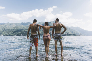 Rückansicht von drei jungen erwachsenen Freunden, die im Comer See stehen, Como, Lombardei, Italien - CUF10081