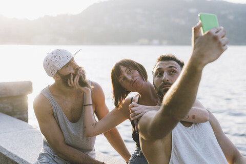 Drei junge Hipster-Freunde machen ein Selfie am Wasser, Comer See, Lombardei, Italien, lizenzfreies Stockfoto