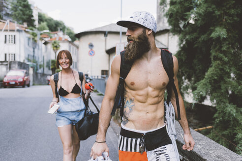 Junges Paar in Badekleidung und Rucksäcken beim Spaziergang in Como, Lombardei, Italien - CUF10094