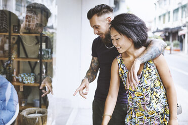 Multi ethnic hipster couple looking and pointing at shop window, Shanghai French Concession, Shanghai, China - CUF10102