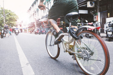 Taille eines jungen männlichen Hipsters beim Radfahren auf der Straße, Shanghai French Concession, Shanghai, China - CUF10104