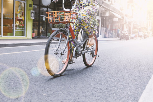 Blick von der Hüfte auf eine Frau, die mit dem Fahrrad die Straße entlang fährt, Shanghai French Concession, Shanghai, China - CUF10105