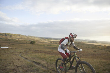 Male mountain biker biking up moorland track - CUF10115