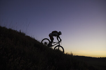 Silhouetted männlichen Mountainbiker Radfahren bergab bei Sonnenuntergang - CUF10120