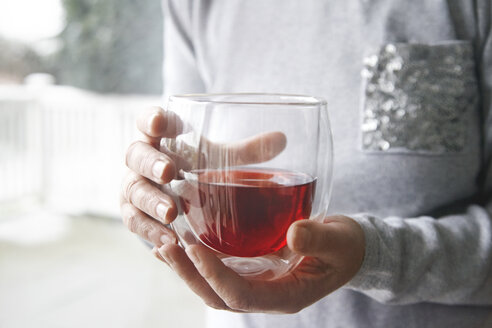 Frau schröpft Glas mit rotem Tee - CUF10122