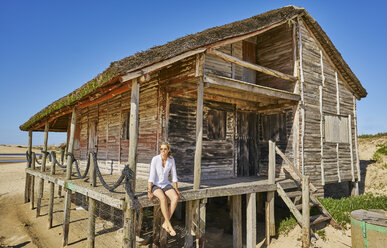 Frau in Veranda einer Holzhütte schaut weg, Polonio, Rocha, Uruguay, Südamerika - CUF10182