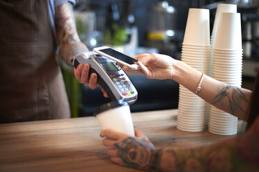 Eine Kundin bezahlt ihren Kaffee mit dem Handy - CUF10223