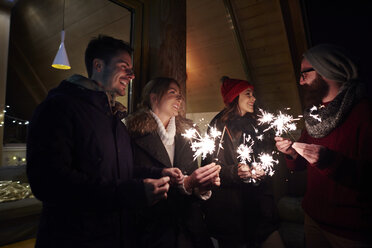 Friends playing with sparklers by chalet - CUF10233