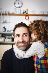 Girl whispering to father in kitchen - CUF10265