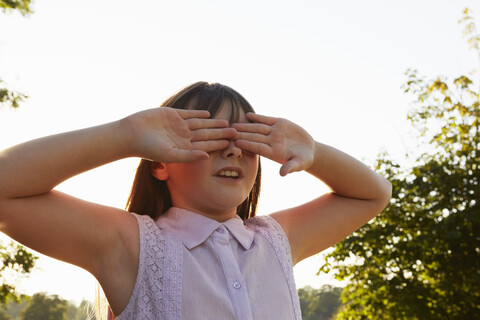 Mädchen verdeckt Augen beim Versteckspiel im Park, lizenzfreies Stockfoto