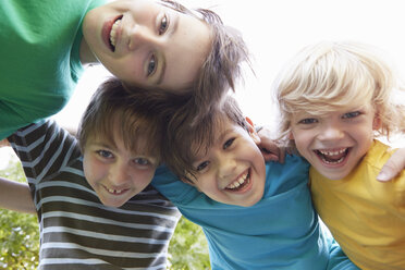 Low angle view of four boys with arms around each other in park - CUF10350